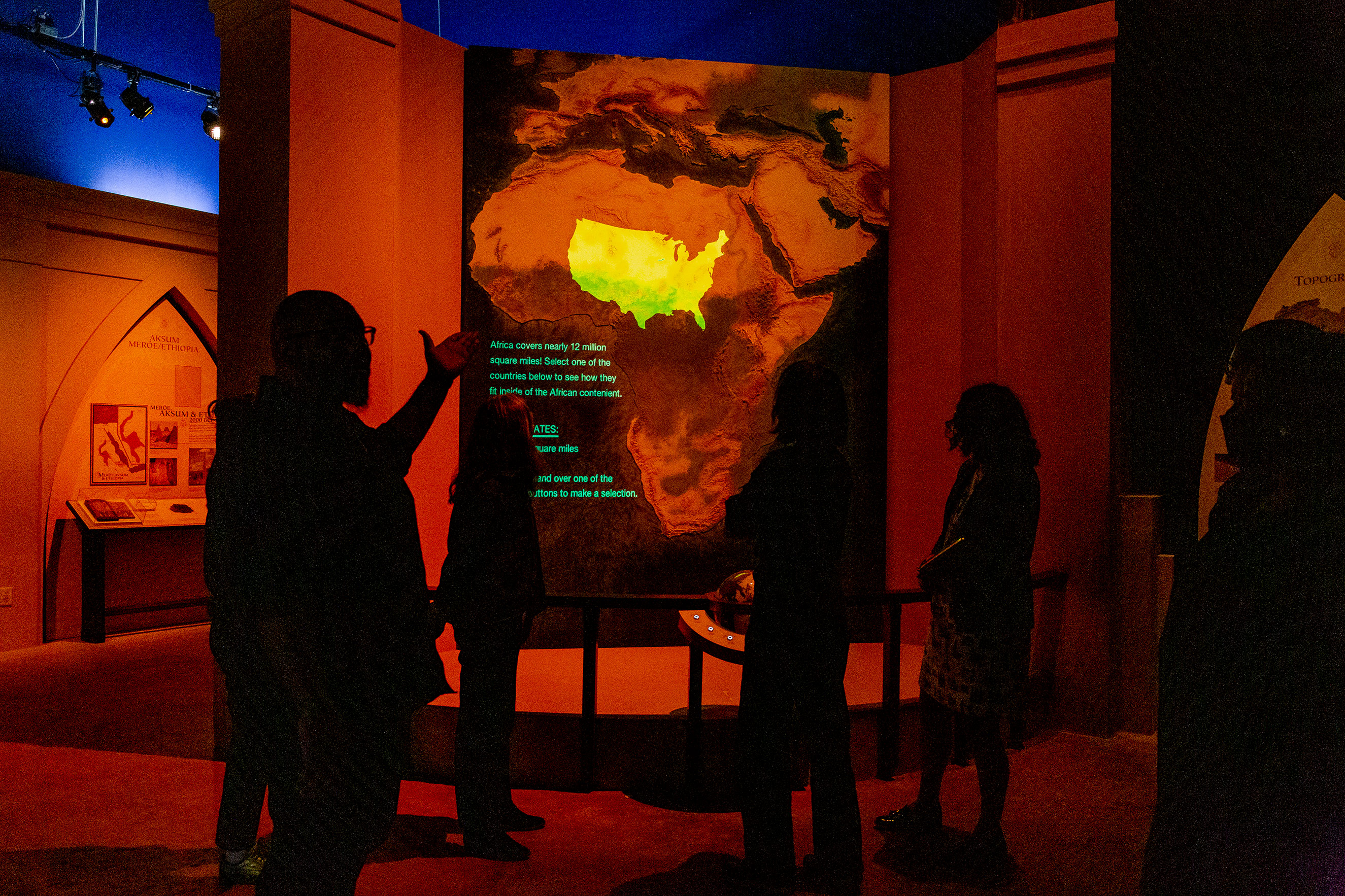 A map of Africa seen through a red light filter. Superimposed is a map of the United States. The size of the United States is dwarfed by Africa.