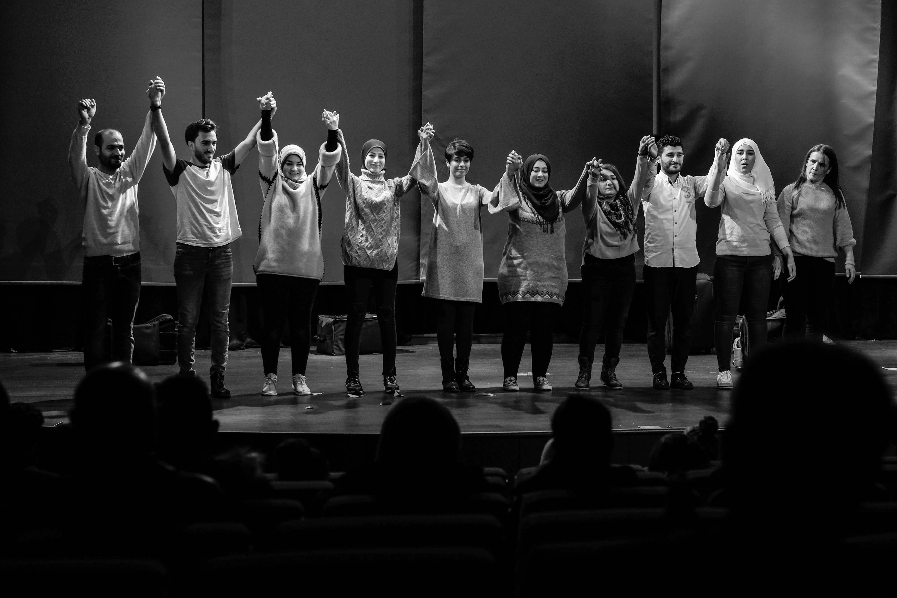  A series of black-and-whie images showing actors on a stage while moving around, holding hands and bowing in a line, standing in two lines across from each other holding ropes and in a single line dancing.