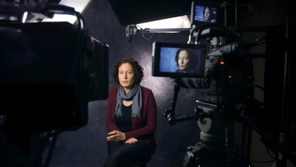 Amy Brown sits in front a camera with her face showing on the monitor.