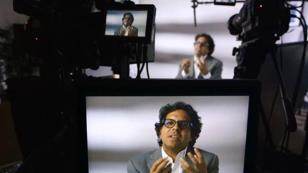 Edgar Altamirano sitting in front of a camera, and gesturing on the monitor.