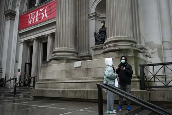 Two tourists wear protective masks while standing in front of the Metropolitan Museum of Art