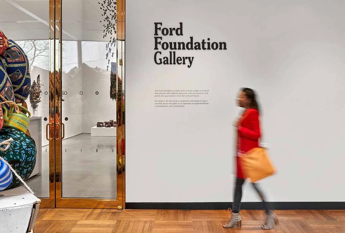 Woman in red coat walking toward 奥五 Ford Foundation Gallery doors