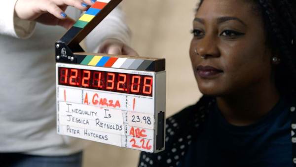 Alicia Garza sitting behind a someone using a film marker. 