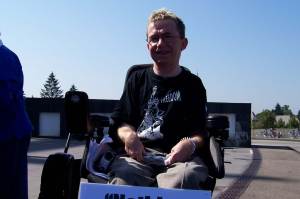 Young disabled man in a wheelchair with a sign that reads "nothing about us, without us." Photo: elisney via Flickr