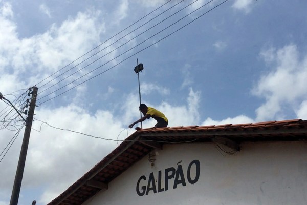 Person setting up wireless antenna on roof in an indigenous community in Brazil.