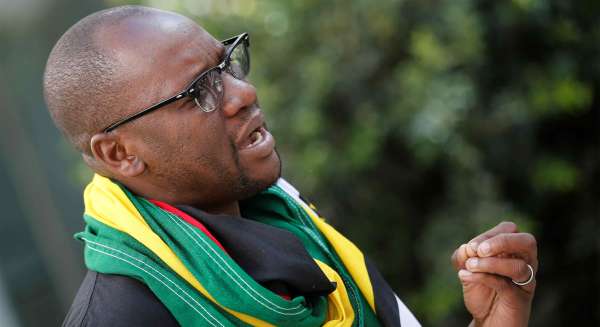 Pastor Evan Mawarire speaks during his interview with Reuters in Johannesburg. He is wearing glasses and a green, yellow, and red scarf. 