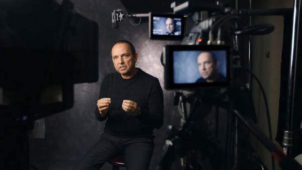 Teddy Crus sitting on a film set in front of multiple cameras with his face displayed on all monitors. 