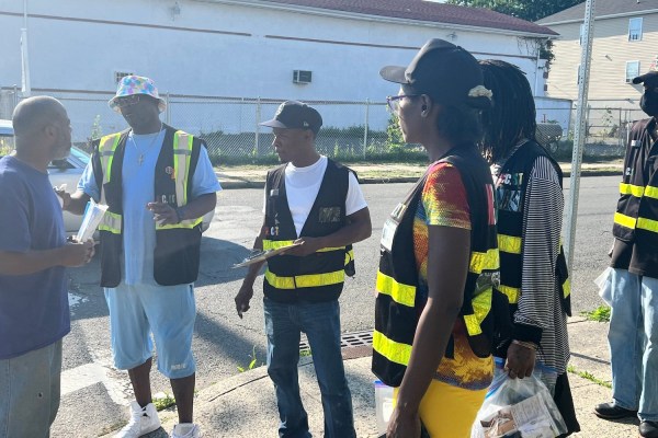 Members of the Newark Community Street Team standing in Newark's South Ward, engaged in conversation and waiting for something.