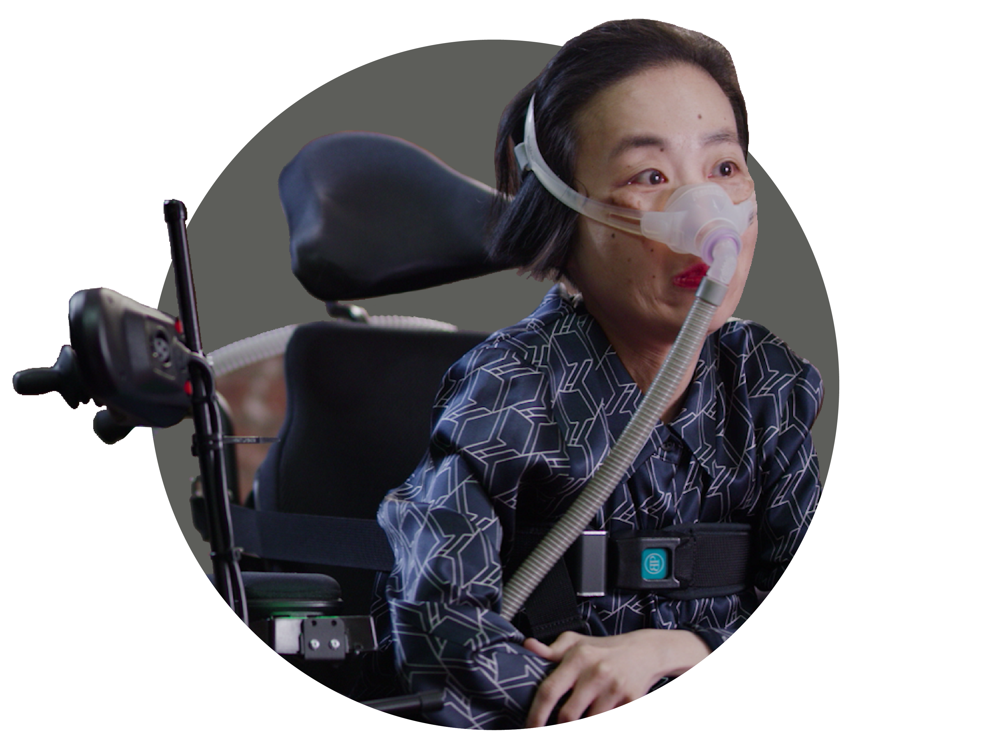 Alice Wong, an Asian American woman in a wheelchair wearing a mask over her nose attached to a tube for a BiPAP machine that helps her breathe. She is wearing a navy striped shirt and dark pants.